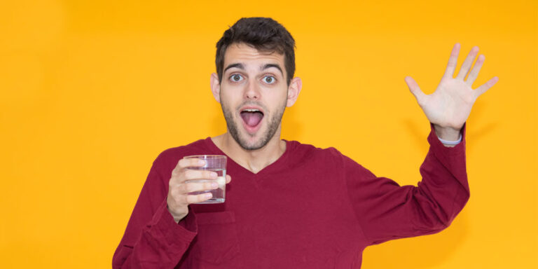 ragazzo stupito che tiene in mano un bicchiere d'acqua